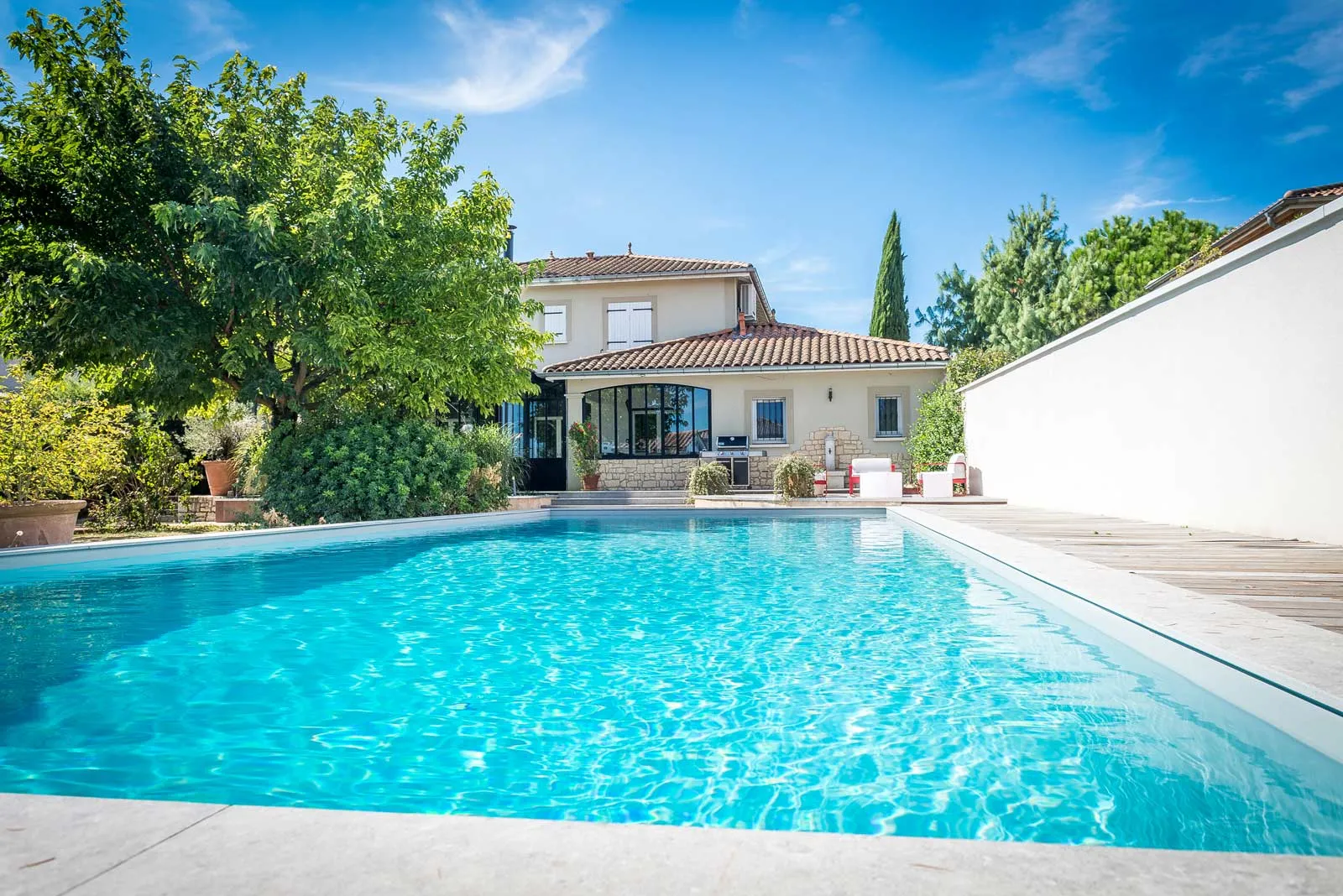 Piscine rectangulaire classique devant une villa en pierre — réalisation Beaulieu Piscines