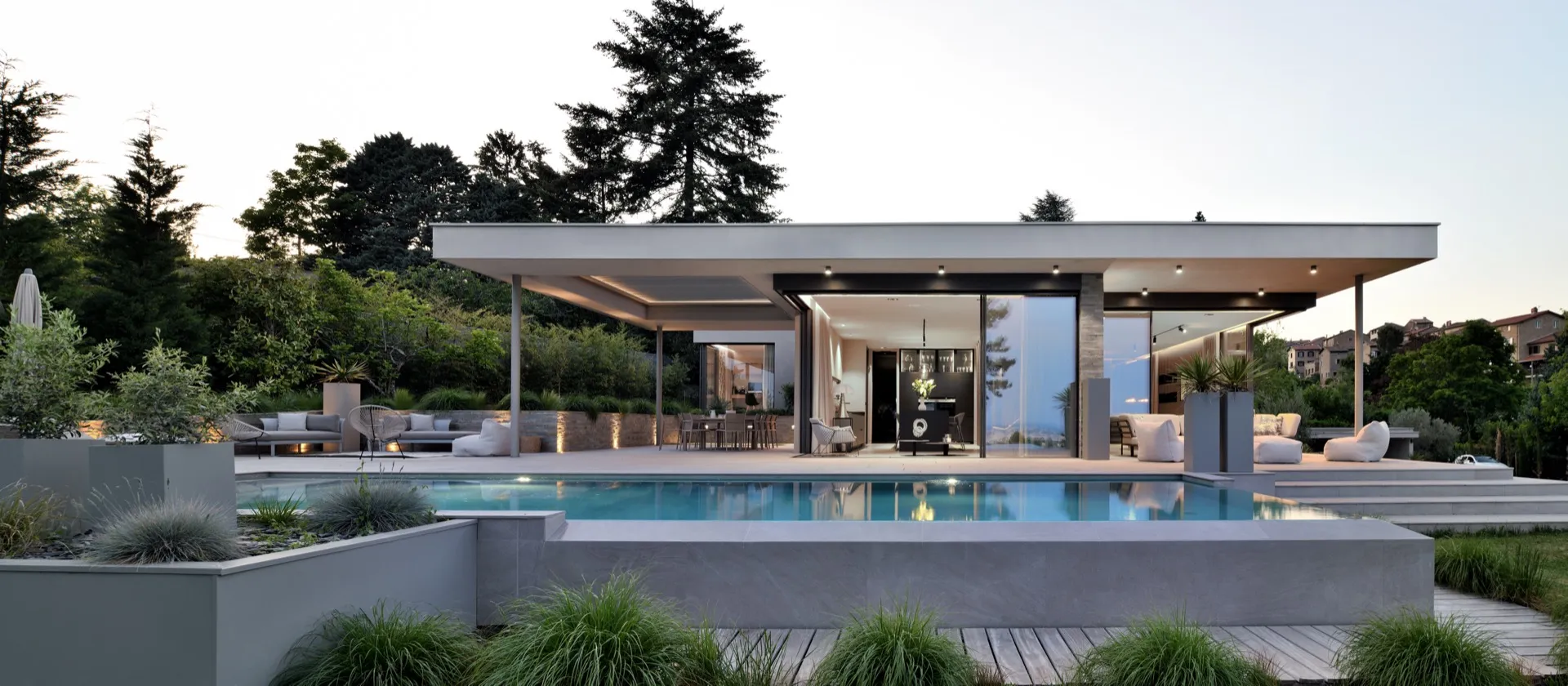 Piscine rectangulaire éclairée au crépuscule devant une villa contemporaine